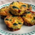 5 onion, green pepper and spinach muffin shaped omelettes on white plate with green squares pattern